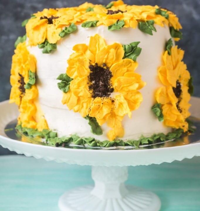 Whole wheat carrot pineapple cake on cake stand with sunflower design buttercream