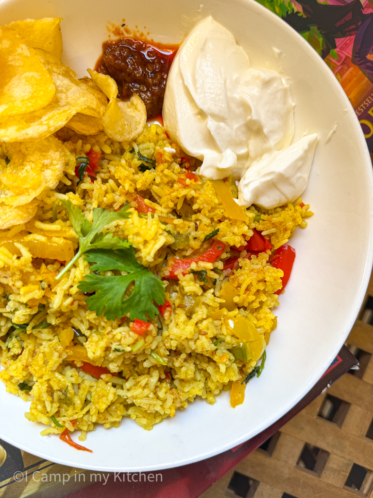 Hearty mixed rice for lunch served with raita and crisp in a bowl